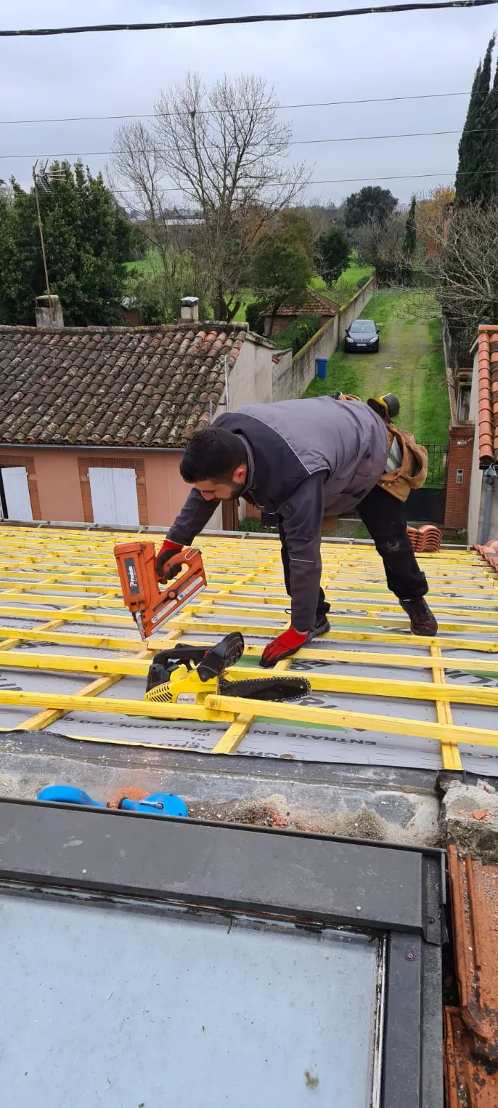 Artisan posant des liteaux pour préparer le support des tuiles