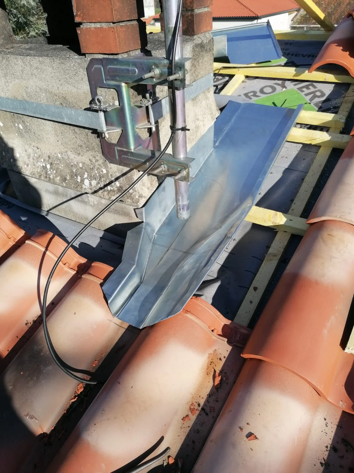 Raccord en zinc posé autour d’une souche de cheminée et d’un conduit sur une toiture en tuiles